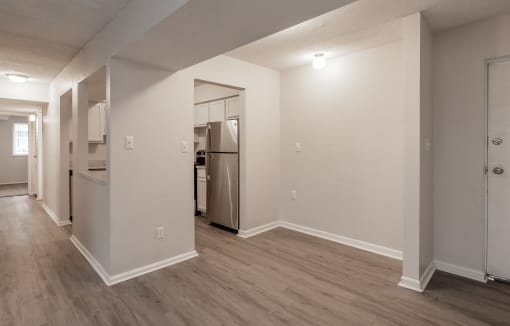a living room with hardwood floors and a kitchen in the background