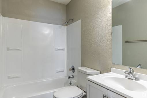 A white bathroom with a toilet, sink, and bathtub.