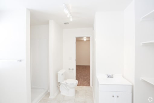 A white bathroom with a toilet, sink, and cabinet.