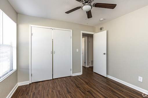 A room with a ceiling fan and a white door.
