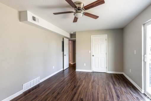 A room with a ceiling fan and wooden floors.