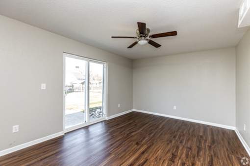 A room with a ceiling fan and sliding glass doors.