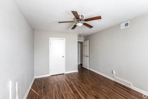 A room with a ceiling fan and wooden floors.