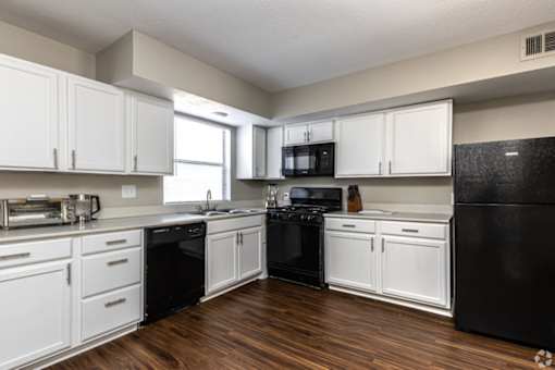 A kitchen with black appliances and white cabinets.