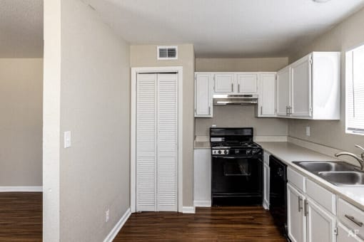 an empty kitchen with white cabinets and black appliances