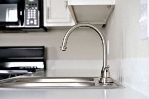 a kitchen sink with a faucet and a microwave