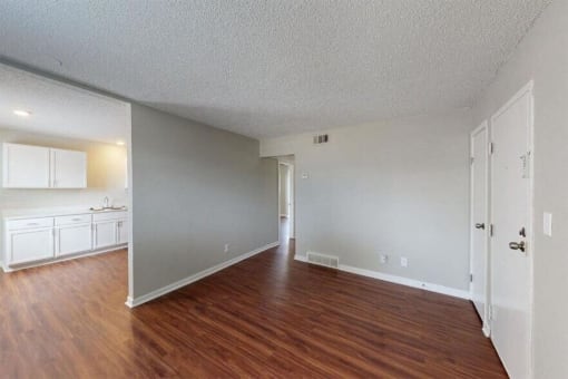 an empty living room and kitchen with wood floors