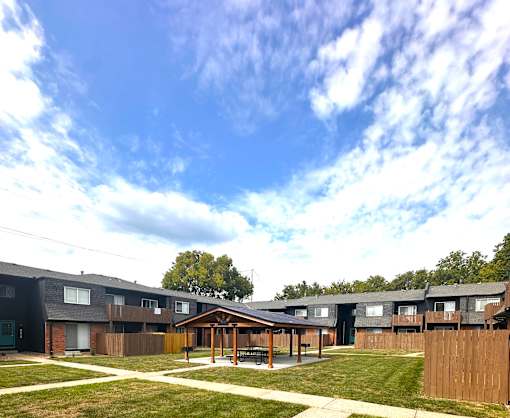 Apartment complex with a gazebo in the middle of a grassy area.