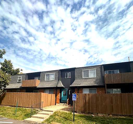Apartment building with a blue door and a wooden fence.
