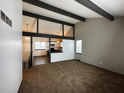 the living room and kitchen of an empty house with a carpeted floor