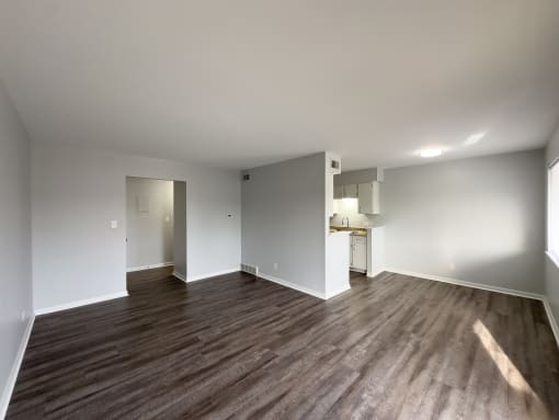 a living room and kitchen with wood flooring and white walls