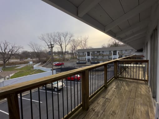a balcony with a wooden railing overlooking a parking lot