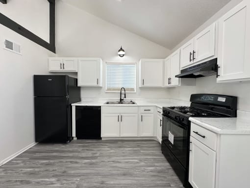 an empty kitchen with white cabinets and black appliances