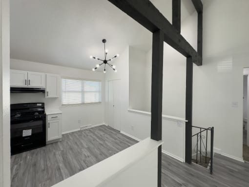 the living room and kitchen of an apartment with white walls and black appliances