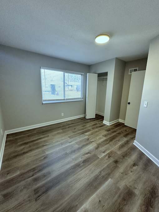 an empty living room with wooden floors and a window