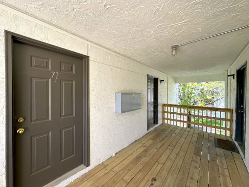 a front porch with a wooden floor and a door with a handle