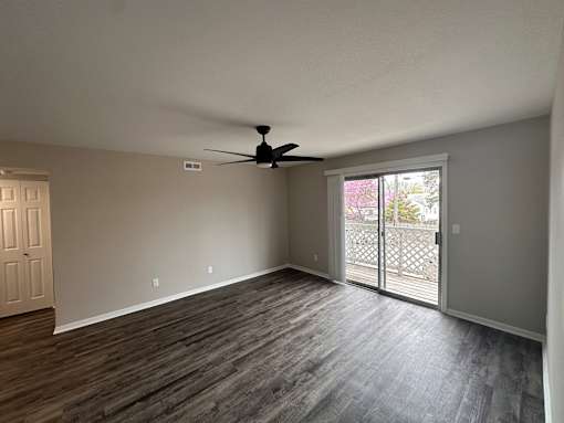 A room with a ceiling fan and sliding glass doors.