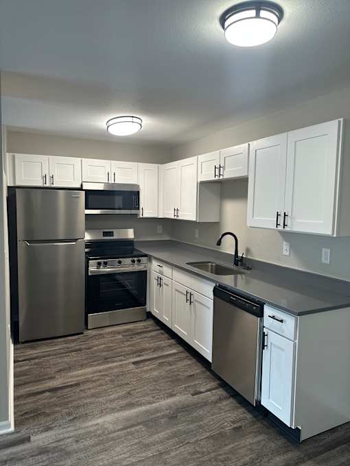 A modern kitchen with a stainless steel refrigerator and a wall-mounted oven.