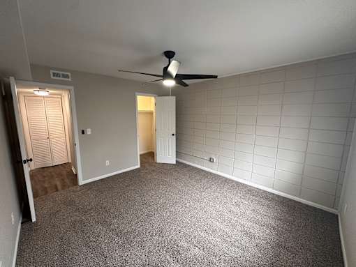 A room with a ceiling fan and tile walls.