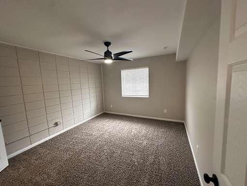 A room with a ceiling fan and a window with blinds.
