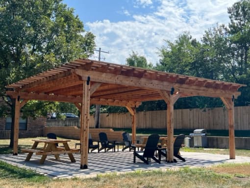 a wooden pergola with a table and chairs under it