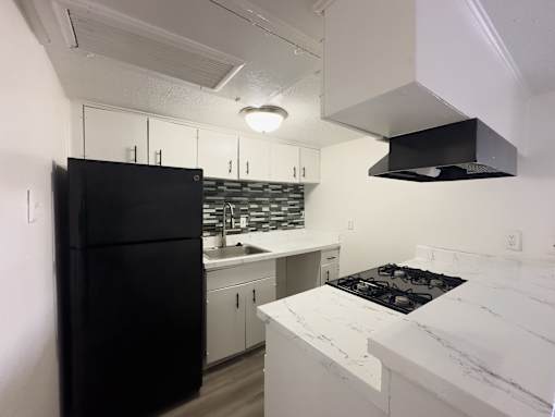 A kitchen with a black fridge and white countertops.