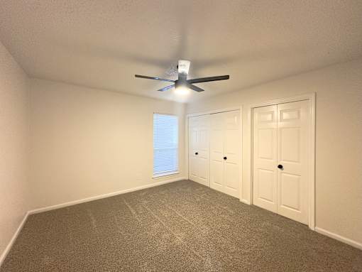 A room with a ceiling fan and two doors.