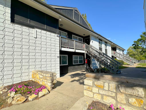the front of a building with a staircase and a stone wall