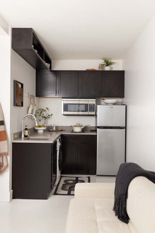 A modern kitchen with a white refrigerator and black cabinets.