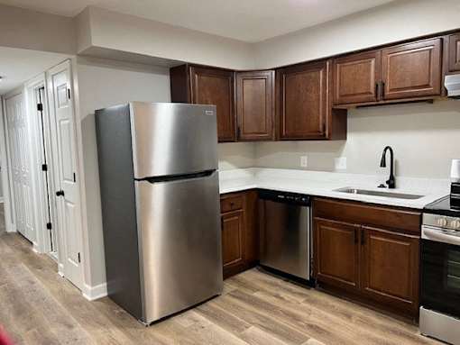 A kitchen with a stainless steel refrigerator and wooden cabinets.