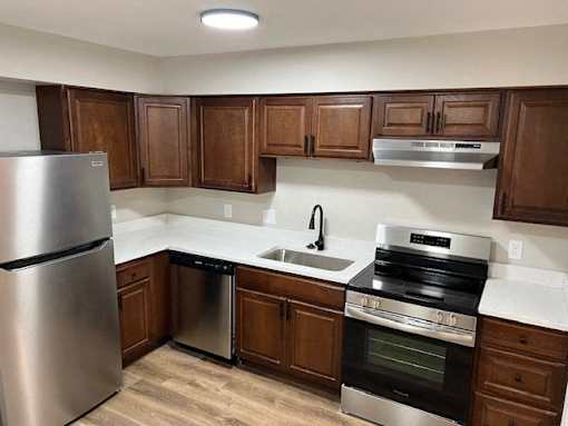 A kitchen with wooden cabinets and a stainless steel refrigerator.