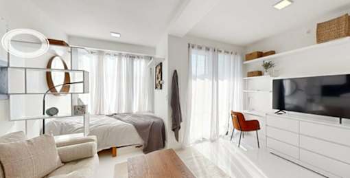 A modern bedroom with a large bed, a chair, and a television.