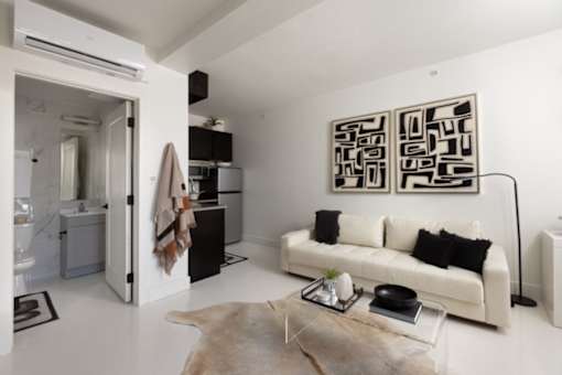 A modern living room with a white couch and a large abstract painting on the wall.