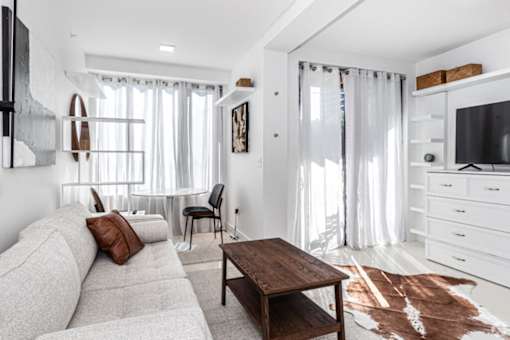 A living room with a grey sofa, a wooden coffee table, and a television.