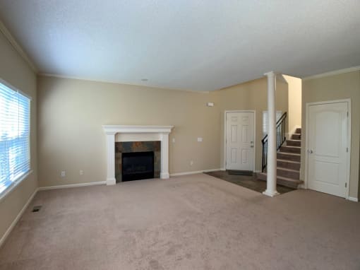an empty living room with a fireplace and a staircase