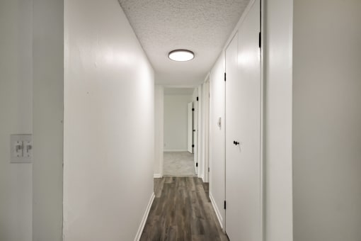 a hallway with white walls and wood floors