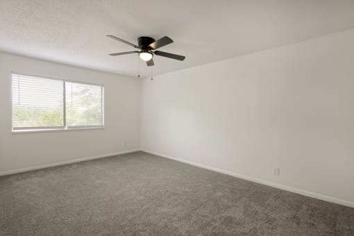 an empty room with a ceiling fan and a window