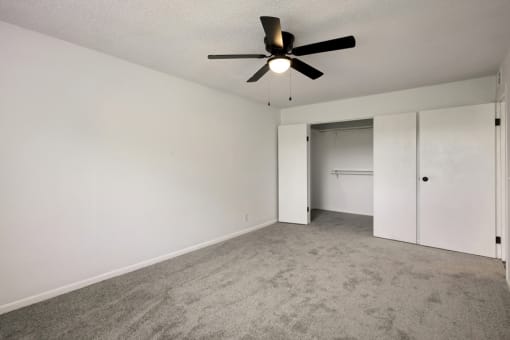 an empty living room with a ceiling fan and white walls