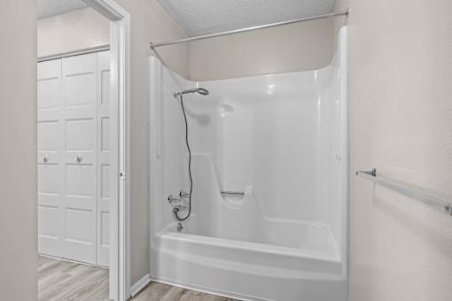 A white bathtub with a shower head and a white door.