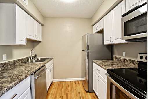 A kitchen with a granite counter top and stainless steel appliances.