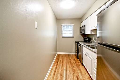 A kitchen with wooden floors and white cabinets.