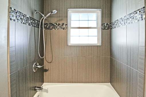 A bathroom with a white tub and a window.
