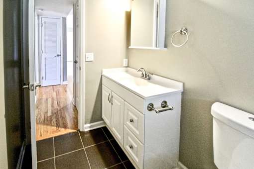 A white sink with a mirror above it and a white towel hanging on the wall.