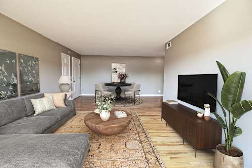 A living room with a grey couch, a coffee table, a TV, and a plant.