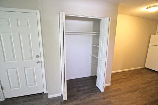 A white door is open to a room with a white fridge.