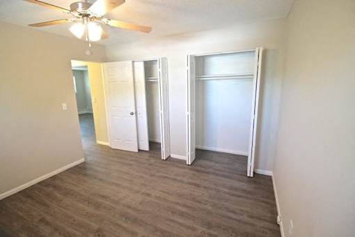 A room with a ceiling fan and sliding doors.