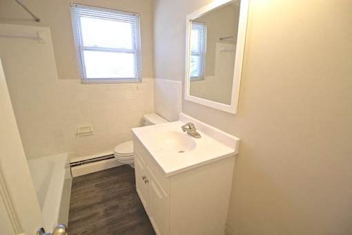 A white bathroom with a toilet, sink, and mirror.