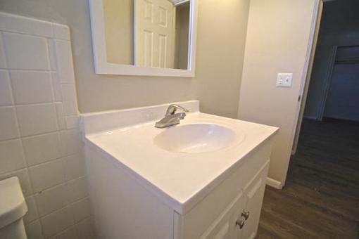 A white bathroom sink with a white cabinet and a white mirror.