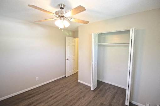A room with a ceiling fan and a doorway leading to another room.