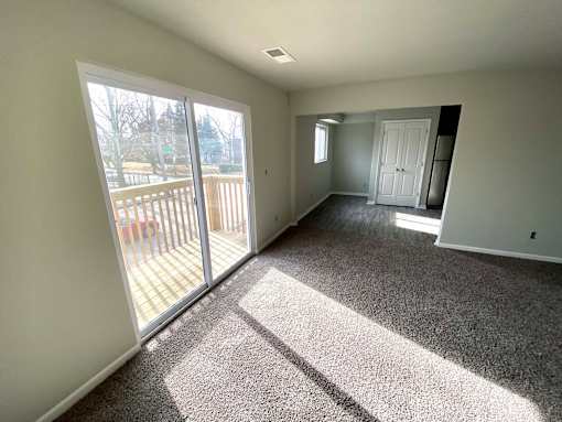 A sunny day with a carpeted room and sliding glass doors.